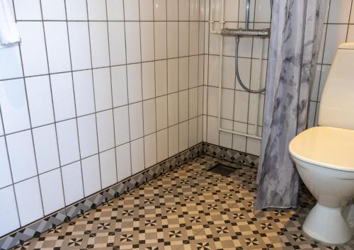 a bathroom with a toilet and a tiled floor at Hotel Angmagssalik in Tasiilaq