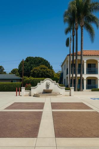 a building with a fountain and palm trees at LYFE INN & SUITES by AGA - LAX Airport in Inglewood