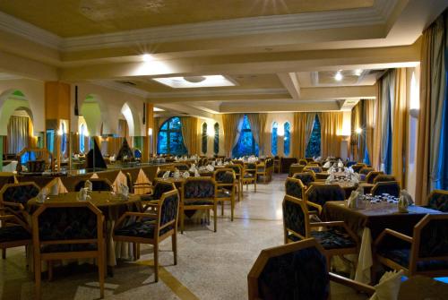 a dining room with tables and chairs and blue curtains at Chems Le Tazarkount in Afourer