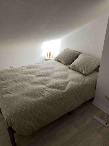 - un lit avec deux oreillers et une lampe dans une chambre dans l'établissement Refuge sur la corniche ! 5 minutes de St-Gilles, à Saint-Hilaire-de-Riez