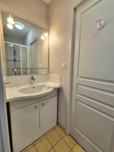 La salle de bains est pourvue d'un lavabo, d'un miroir et d'une porte. dans l'établissement Le Clos Des Farges #Clim#Parking#Terrasse, à Clermont-Ferrand