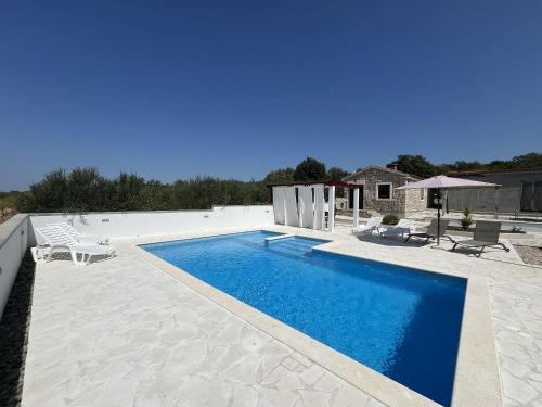 een zwembad in een tuin met stoelen en een huis bij Villa Villa Nadin in Nadin