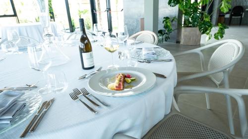 a white table with a plate of food and a bottle of wine at Terreforti Luxury Village in Agrigento