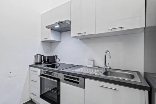 a white kitchen with a sink and a stove at City Center I At Stadtpark I 1 Minute to Metro in Vienna