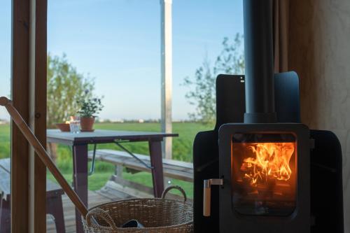 a wood burning stove in a room with a table at Luxe Wikkelhouse met hottub 'Dompel' in Hoogwoud