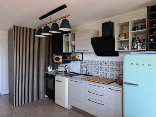 a kitchen with white cabinets and a blue refrigerator at logement de charme en bord de plage in Lumio