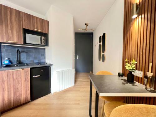 une cuisine avec un comptoir noir et des placards en bois dans l'établissement Art Deco Studio avec terrasse aux portes du parc, à Chasseneuil-du-Poitou