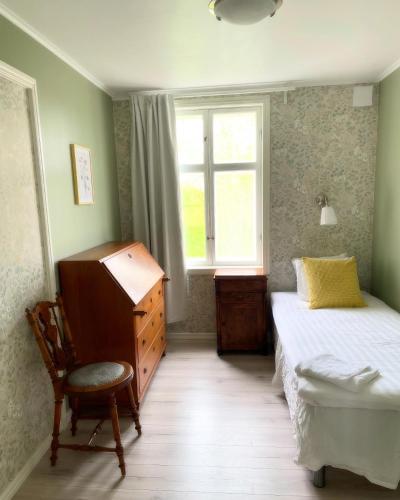 a bedroom with a bed and a window and a chair at Pensionat Haga Öland in Löttorp