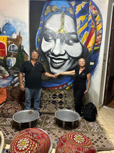 a man and a woman standing in front of a mural at Cecilia Hostel in Cairo