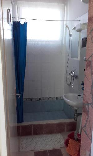 a bathroom with a shower with a blue shower curtain at János Nyaraló in Balatonmáriafürdő