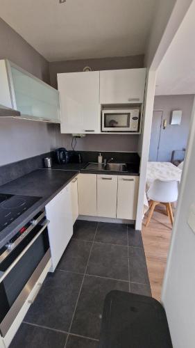 une petite cuisine avec des armoires blanches et un micro-ondes dans l'établissement Grand et Cosy T2 à 10min des facultés, à Montpellier