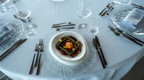 a white bowl of food on a table with silverware at Terreforti Luxury Village in Agrigento