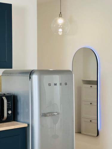 - un réfrigérateur en acier inoxydable dans une cuisine avec un miroir dans l'établissement Appartement Jules Ferry - centre, à Saumur