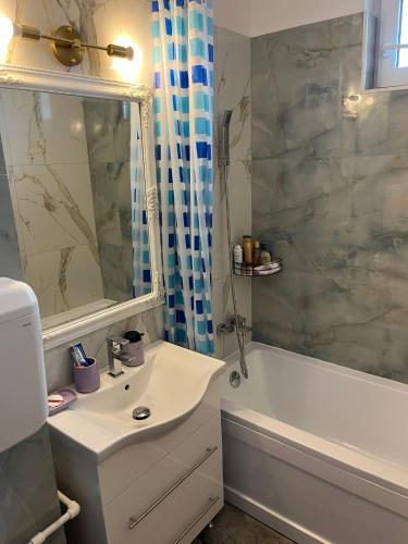 a bathroom with a sink and a tub and a mirror at CX Family Apartment in Bucharest
