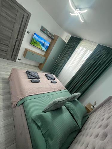 a bedroom with a bed with green sheets and a window at CX Family Apartment in Bucharest