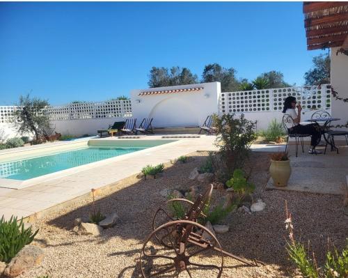 a woman sitting in a chair next to a swimming pool at Al Poggiale - Residenza Mediterranea in Porto Cesareo