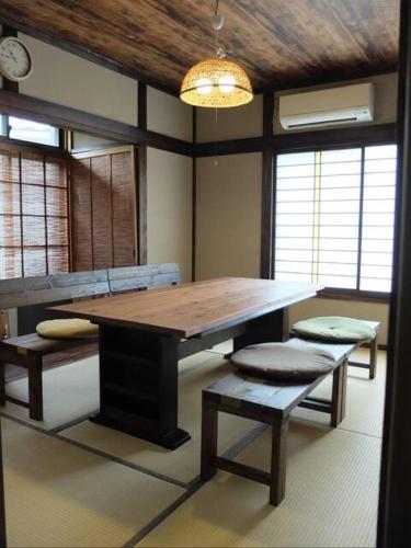 a dining room with a table and benches and a clock at Guest House coco-Rin in Hamamatsu