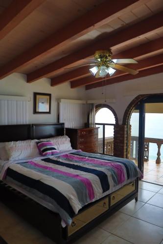 a bedroom with a large bed and a ceiling fan at Encantó del Mar - Beachfront house in Tijuana