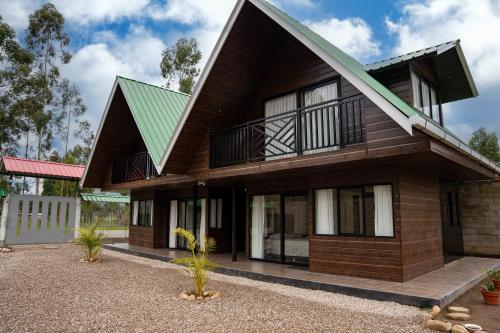 a wooden house with a green roof at Prana Cabins Oxapampa in Oxapampa