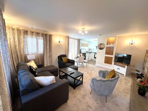 a living room with a couch and chairs and a tv at Ground Floor 2 Bedroom Apt, Onsite Parking, Edge of Glastonbury and Street in Street