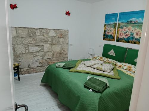 una camera con un letto verde e una parete in pietra di Appartamento bilocale ERICA a Monteriggioni