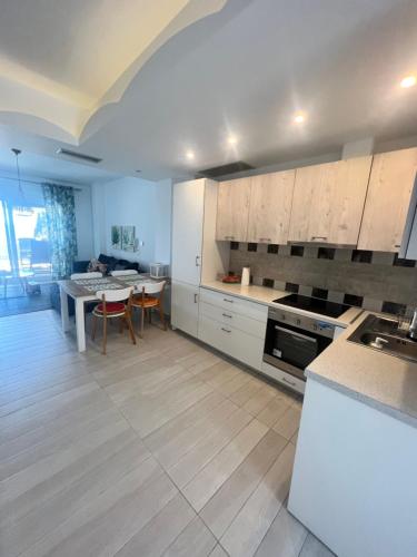 a kitchen with white cabinets and a table and a dining room at Nea Peramos Apartment SeaFront in Néa Péramos
