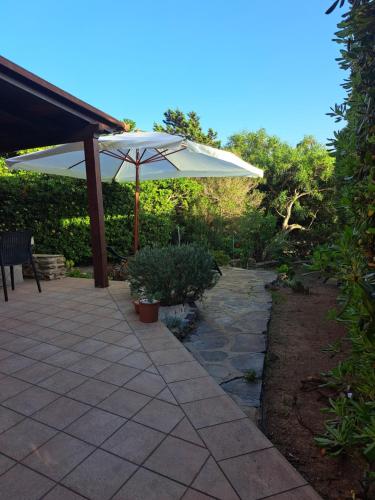 a patio with an umbrella and a stone walkway at Residenza Ponente in Stintino
