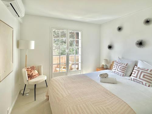 une chambre blanche avec un grand lit et une chaise dans l'établissement Rénové 2025 - 6 personnes - Clim Parking Piscine Terrasse, à Saint-Raphaël