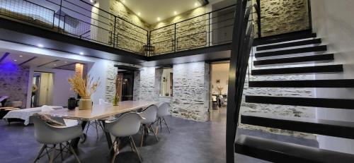 une salle à manger avec une table et des chaises et un escalier dans l'établissement Gite le Parveau, 3 étoiles meublé de tourisme, à La Guiltière