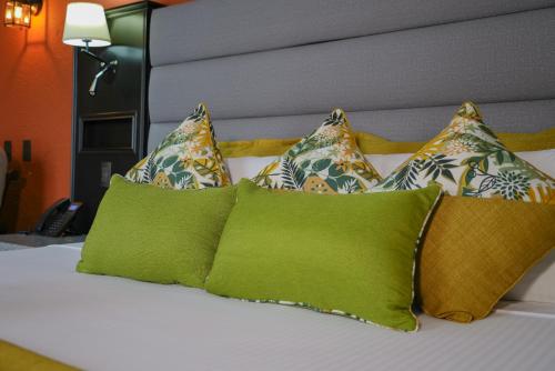 a bed with four green pillows on top of it at Hotel Arenal Springs Resort & Spa in Fortuna