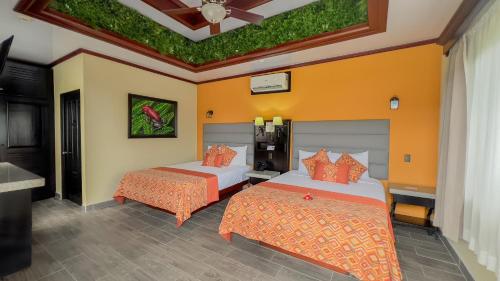 two beds in a room with orange and yellow walls at Hotel Arenal Springs Resort & Spa in Fortuna