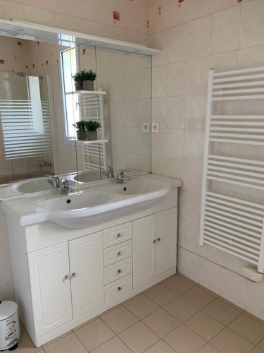 Un baño blanco con lavabo y espejo. en Maison Familiale 6 pers - Orouët, en Saint-Jean-de-Monts