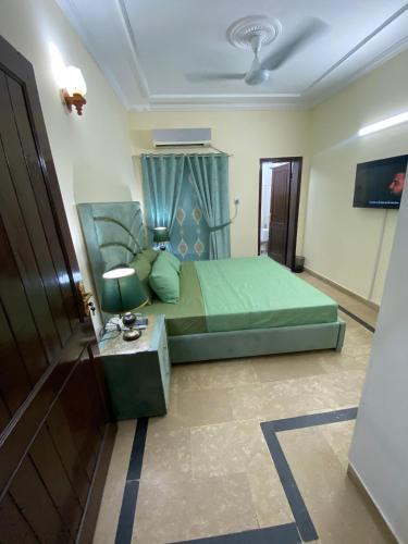 a bedroom with a green bed and a table at Evergreen Escape in Lahore