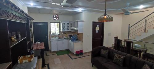 Una sala de estar con un sofá y una cocina. en Evergreen Escape, en Lahore