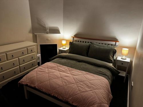 a bedroom with a bed and two lamps on two tables at Cosy Wee Cottage in Monkton