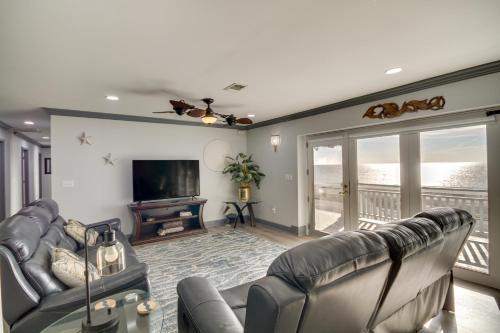 a living room with couches and a television and a balcony at Front Row Beachfront Long Beach Getaway in Long Beach