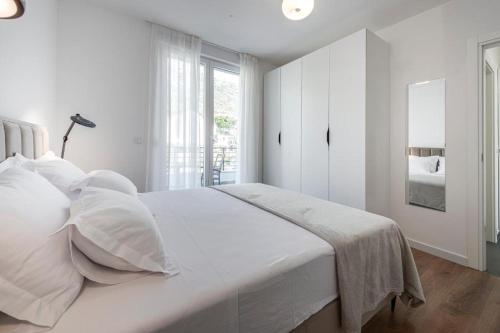 a white bedroom with a large bed with white pillows at Mokos Modern Suite with Sea View and Jacuzzi in Dubrovnik