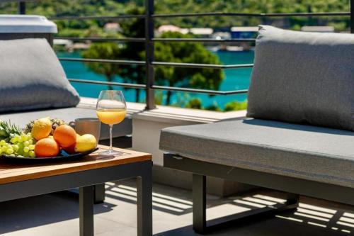 a glass of wine and a bowl of fruit on a table at Mokos Modern Suite with Sea View and Jacuzzi in Dubrovnik