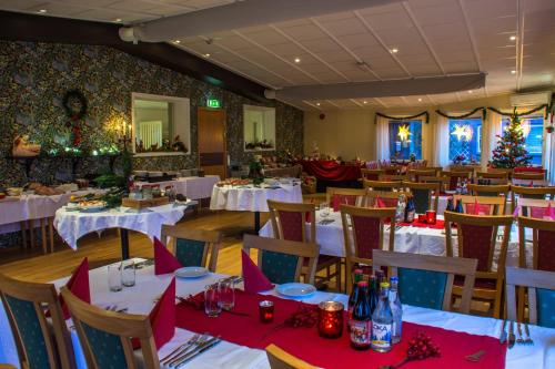 a restaurant with white tables and chairs with christmas decorations at Lungsunds Hotell & Camping in Storfors