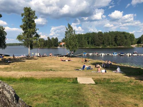 a group of people sitting on the shore of a lake at Lungsunds Hotell & Camping in Storfors