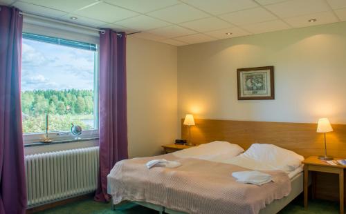 a hotel room with a bed and a window at Lungsunds Hotell & Camping in Storfors