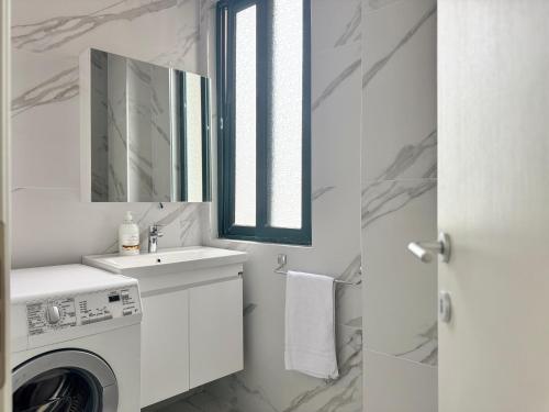 ゴーレムにあるNoAr Luxury Apartamentの洗面台と洗濯機を備えた白いバスルーム