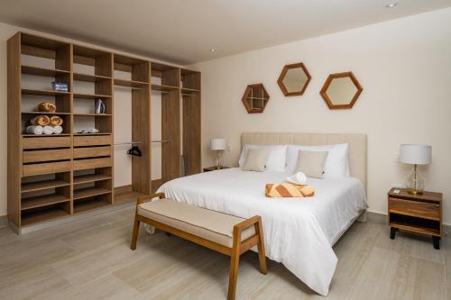 Cumbres Garden luxury apartments في كانكون: غرفة نوم بسرير ابيض كبير ومقعد