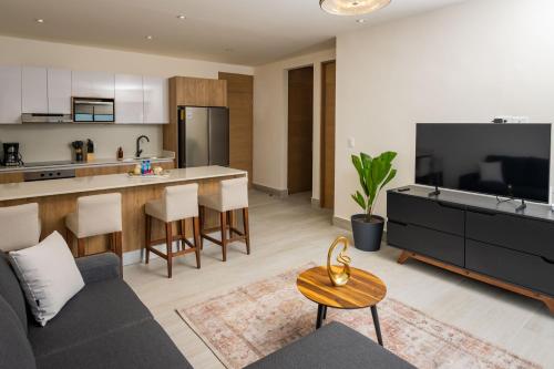 a living room and kitchen with a couch and a table at Cumbres Garden luxury apartments - By Aloja RV in Cancún