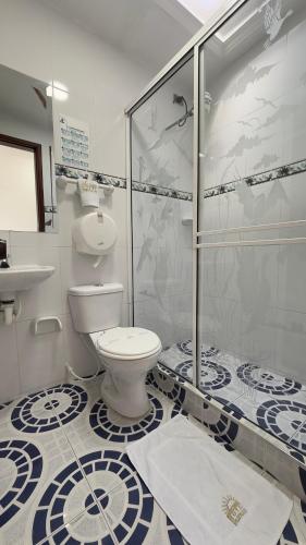 a bathroom with a toilet and a glass shower at Hotel Paipa Inn in Paipa
