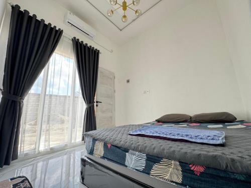 una camera da letto con un letto con tende nere e una finestra di Mila Homestay a Padang