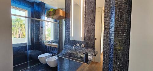 a bathroom with two toilets and a glass shower at Shati Luxury - New, Heated Pool, Sea view Near beach in Fontane Bianche
