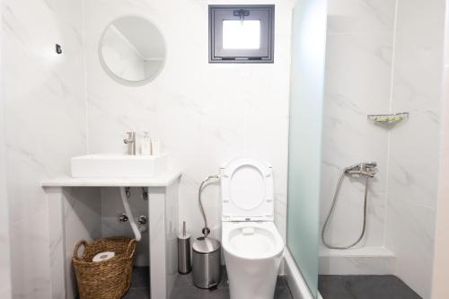 a white bathroom with a toilet and a sink at Paradise Lofts in Asprovalta