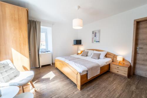 a bedroom with a large bed and a chair at Gästehaus Mack in Trittenheim