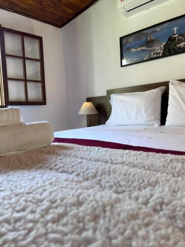 a bedroom with a large bed and a window at Pousada Solar Azul in Miguel Pereira
